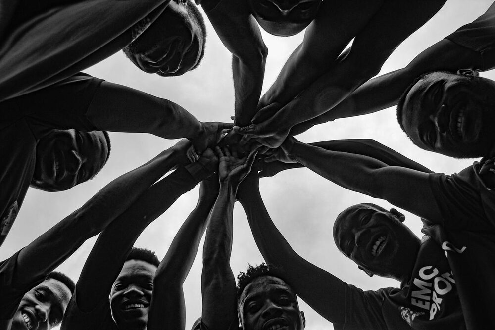 Un gruppo di persone con mani e volti uniti, che rappresenta la cooperazione organizzativa e la resilienza collettiva